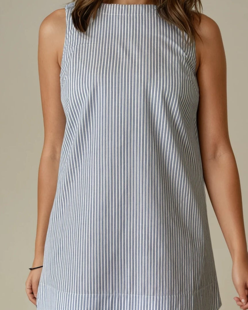 Woman wearing a light blue striped dress against a beige background