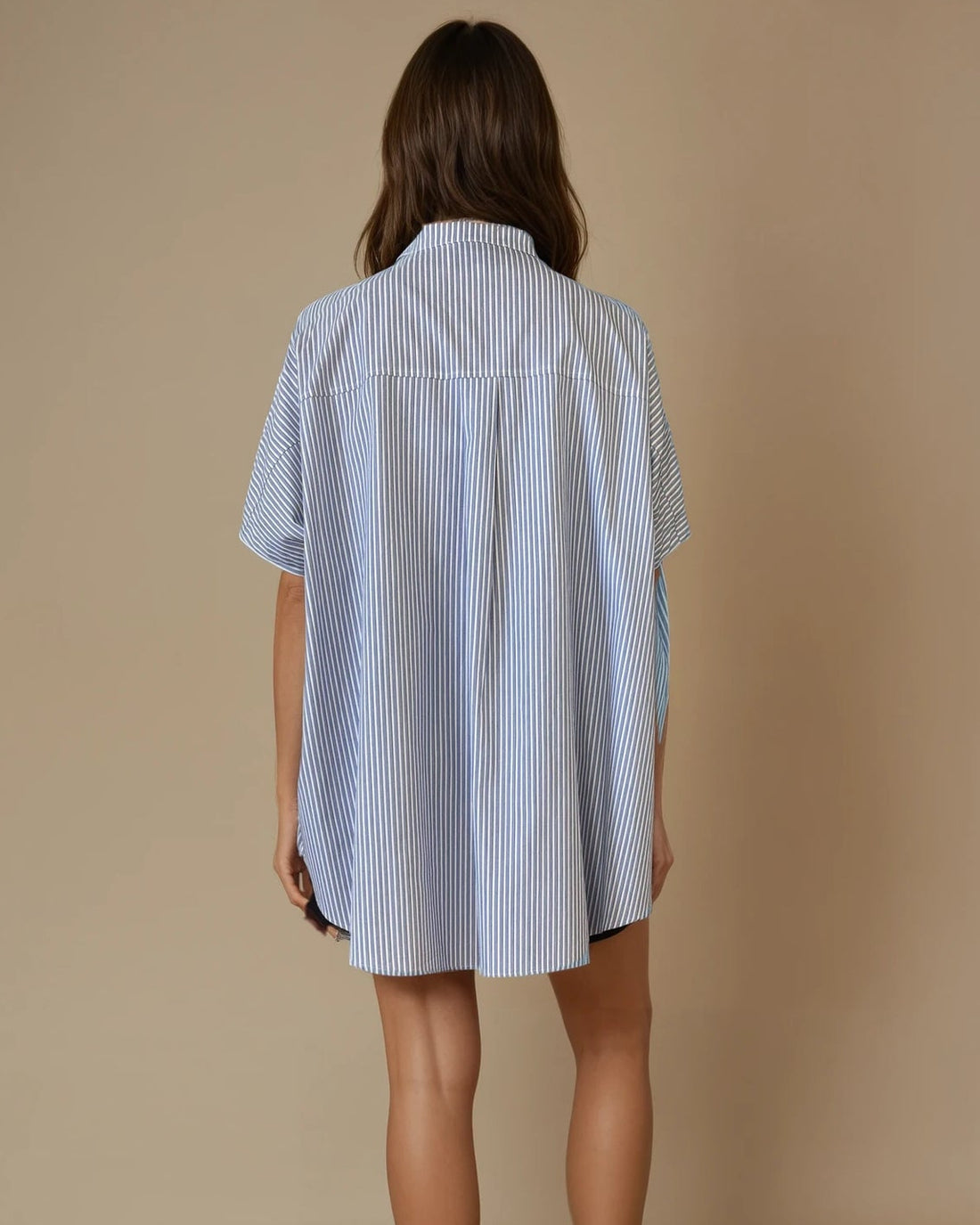 Woman wearing a blue and white striped shirt dress against a beige background